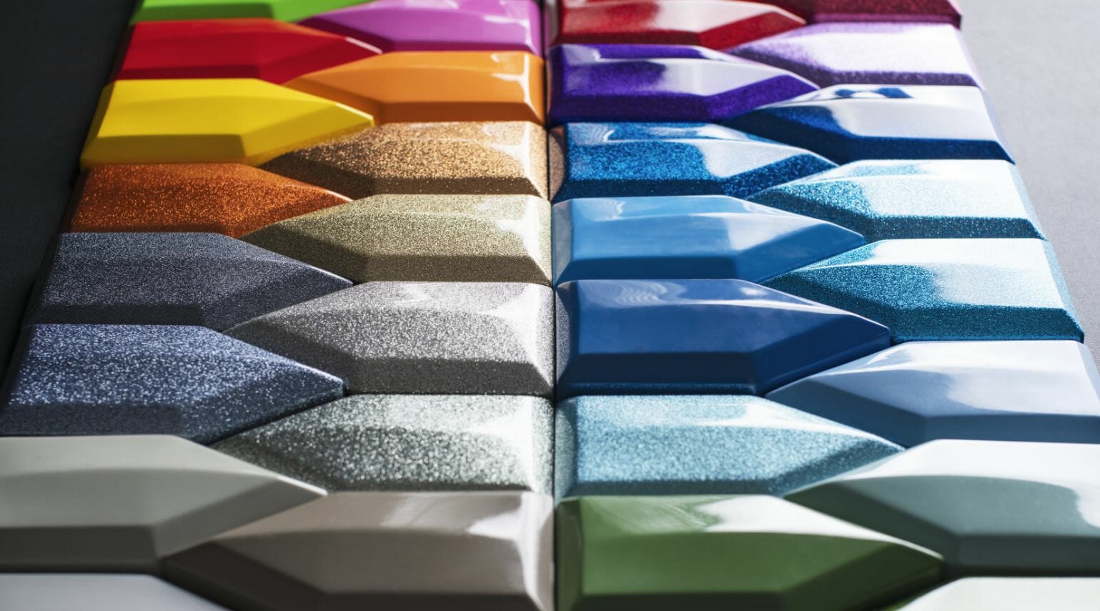 A row of colorful tiles on a black surface resembling wakesurf boats.