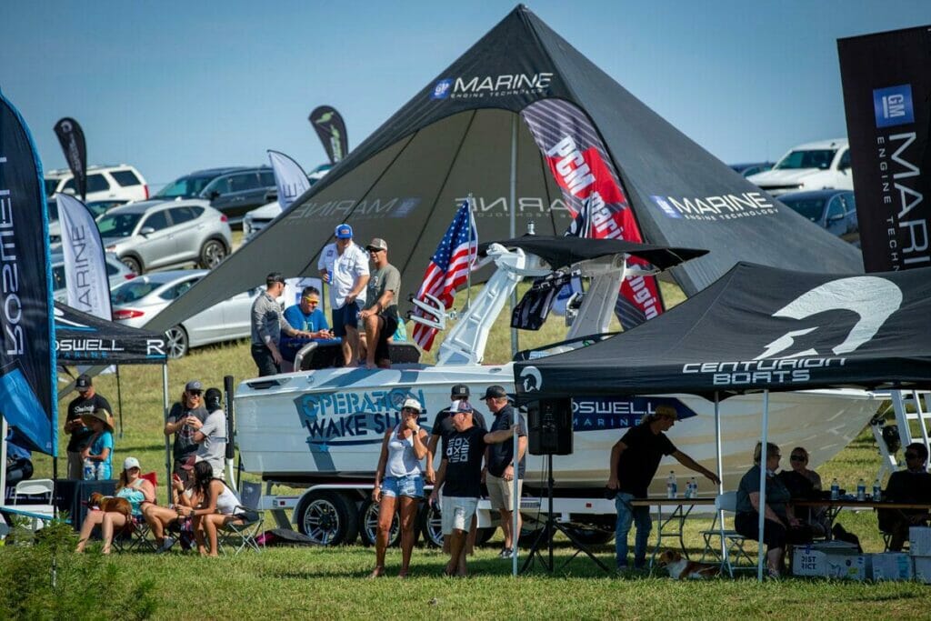A group of people standing around a wakeboat.