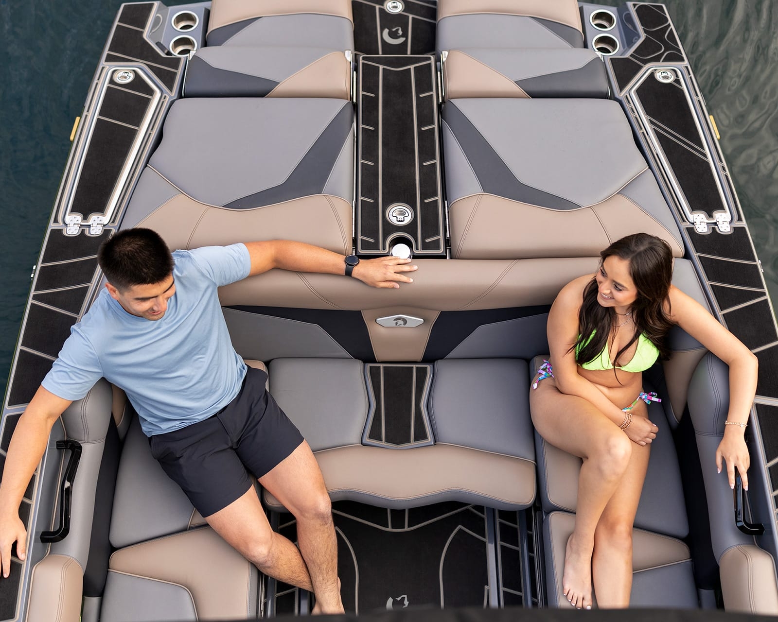 Two people sit and converse on a modern Centurion Fi25, its cushioned seating providing comfort as the boat floats on the water.
