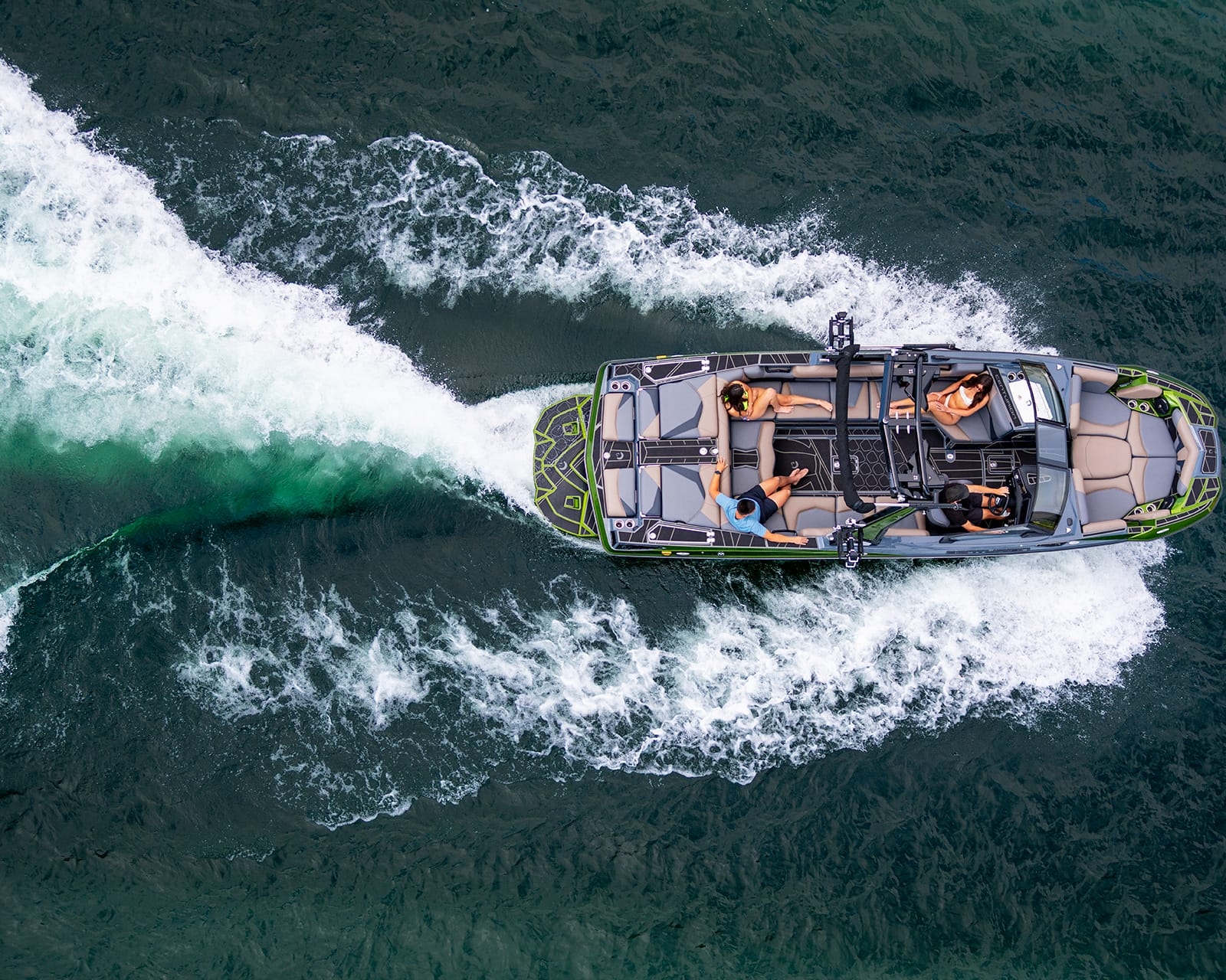Aerial view of a Centurion Fi25 cutting through green water with four people aboard, leaving a striking white wake behind.