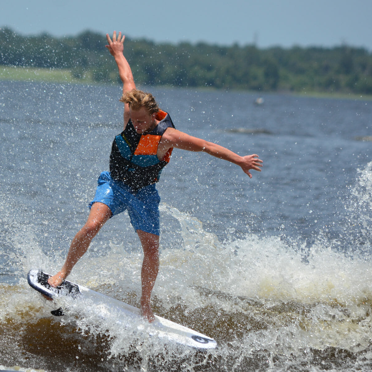 A man riding a wave on a wakesurf board.