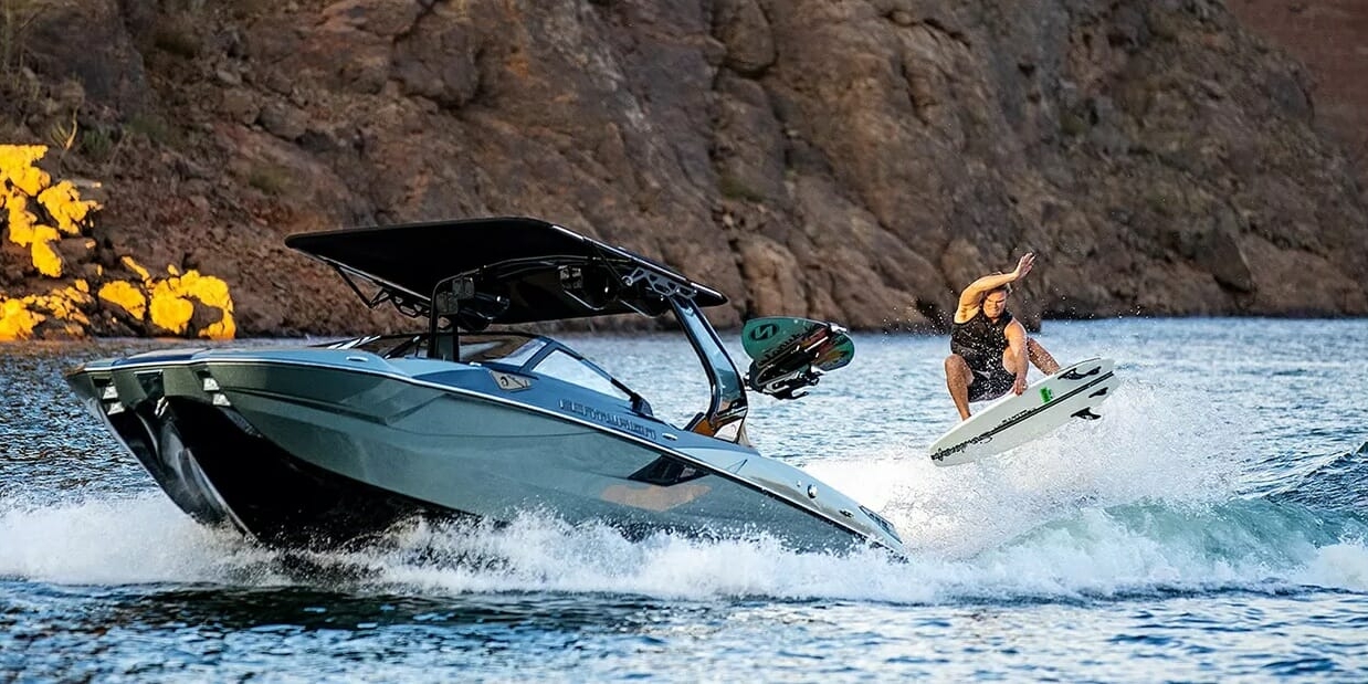 A man is riding a wakesurf board on a boat.