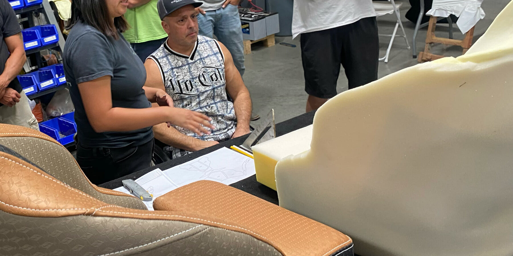 A group of people inspecting a Custom Boat Seat at a workshop.