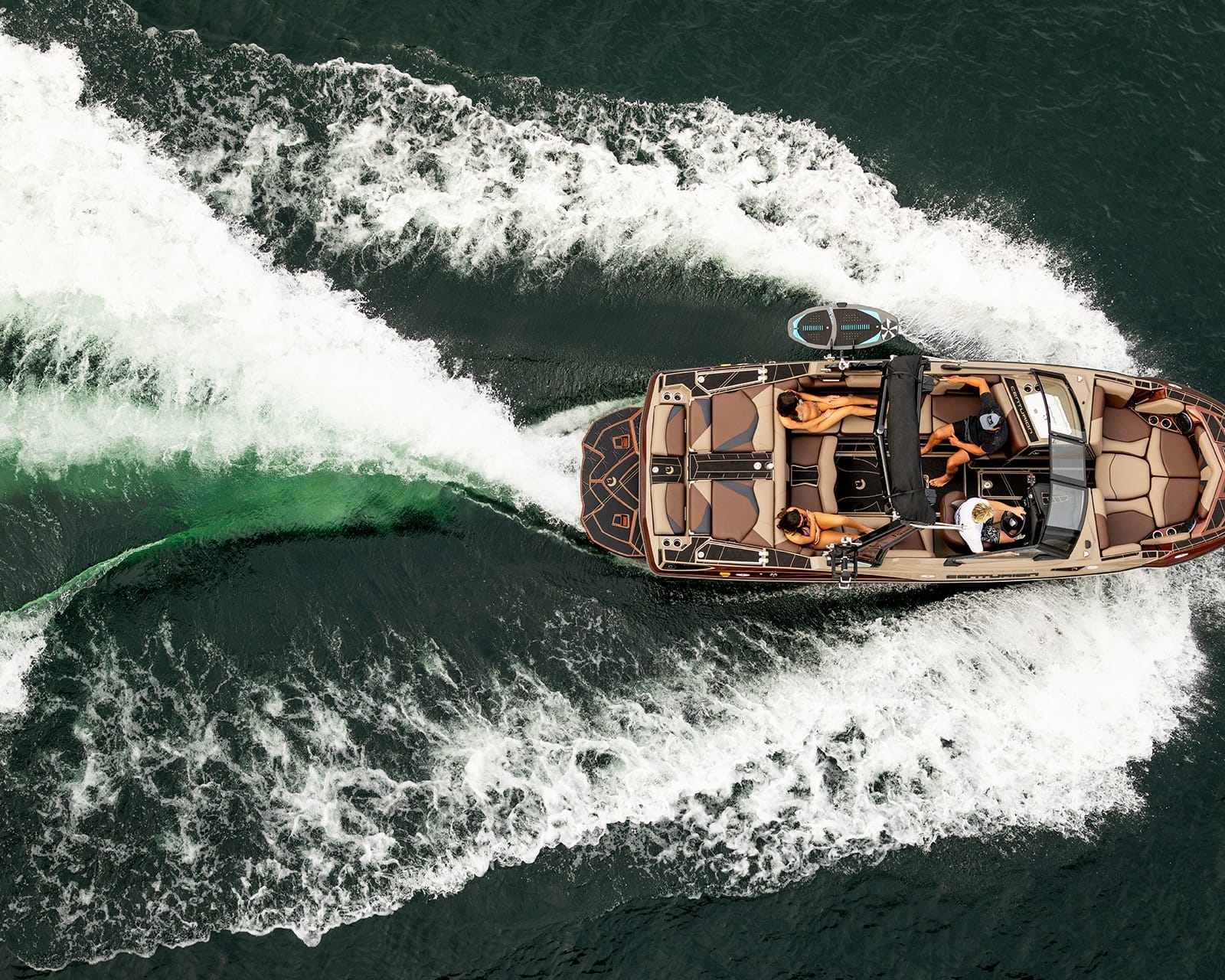 A Centurion Fe22 speeds across the water with four people onboard, carving white waves and a green wake behind this impressive Fe22 Surf Boat.