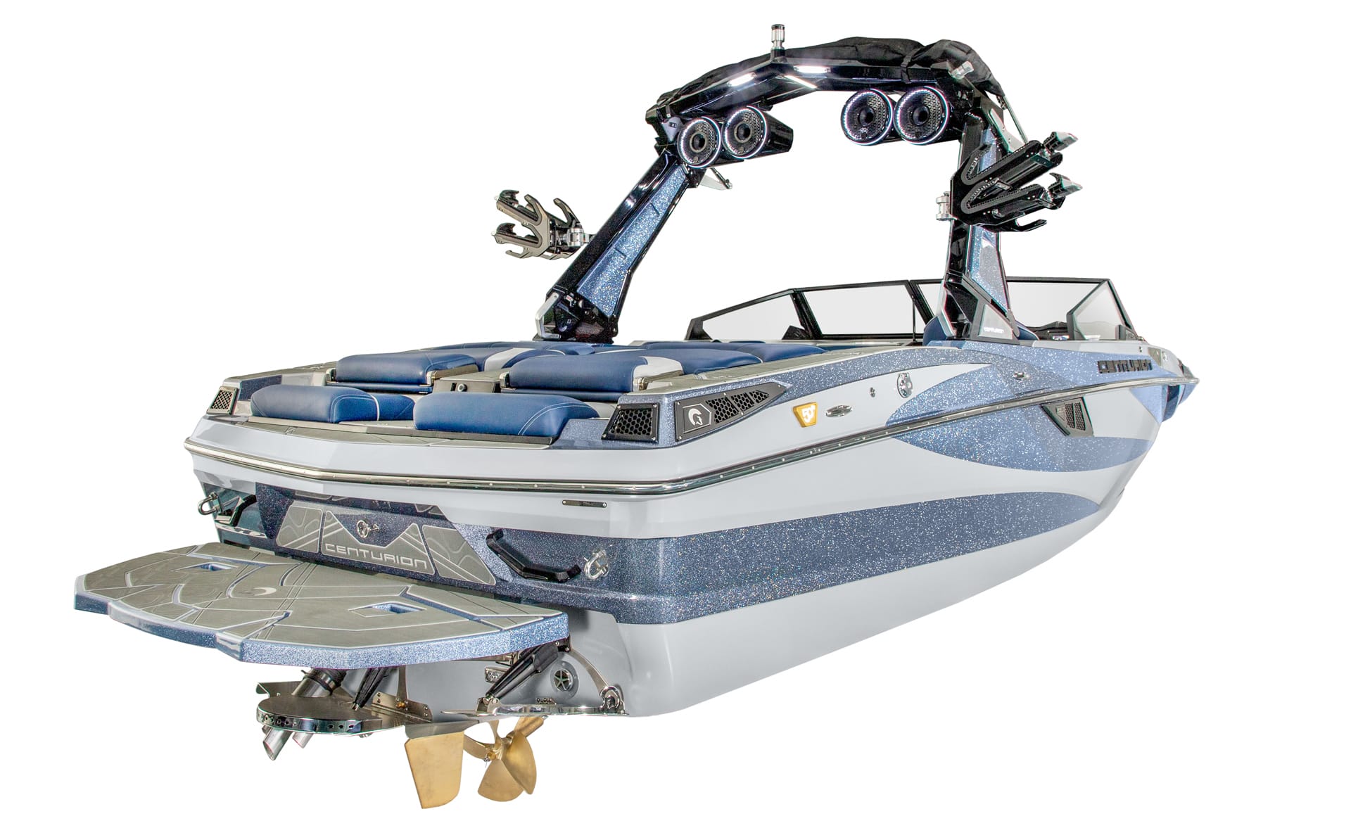A blue and white Centurion Fe22 wakeboarding boat with seating, mounted speakers, a wakeboard tower, and swim platform, viewed from the rear side angle.