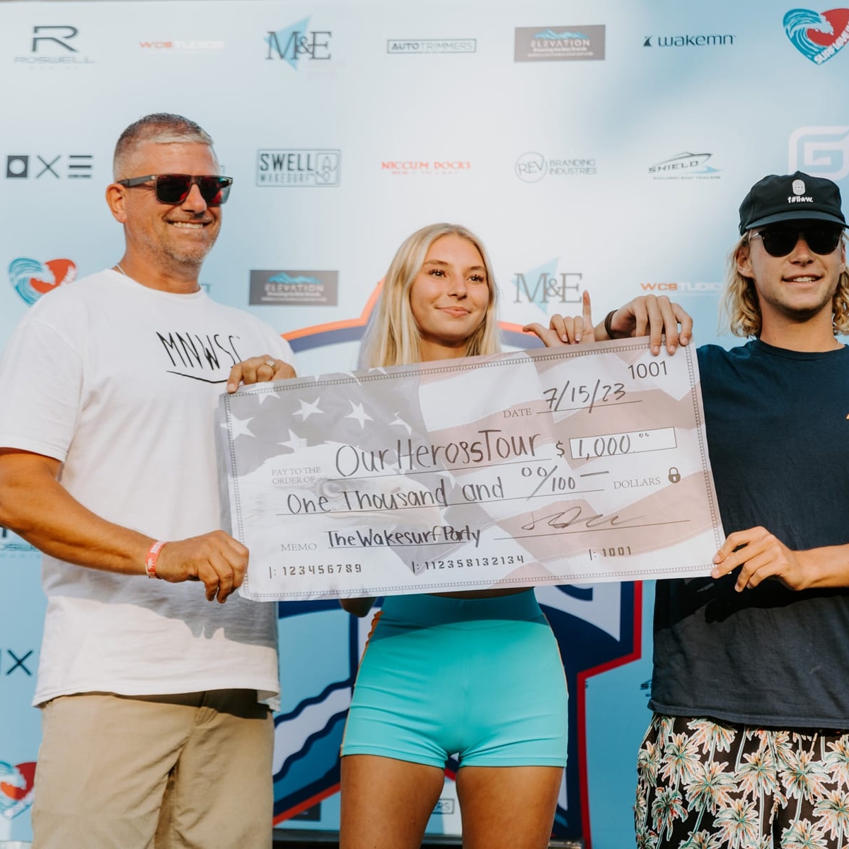 Three people standing next to each other holding a check.