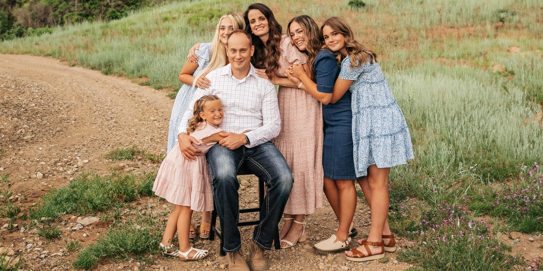 A family posing for a photo on a dirt road.