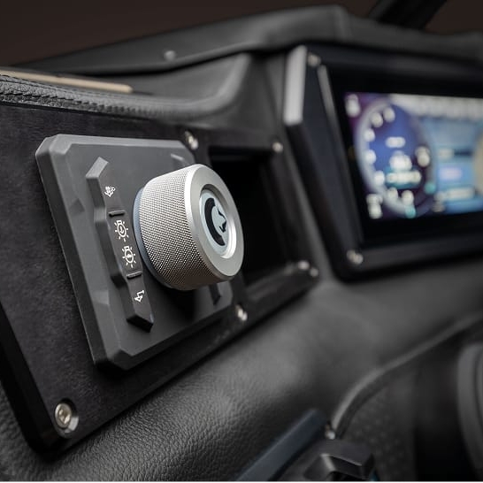 A close-up of a Fe Series vehicle dashboard showing a textured control knob with labeled buttons and a digital display screen in the background, highlighting its Features Personal.