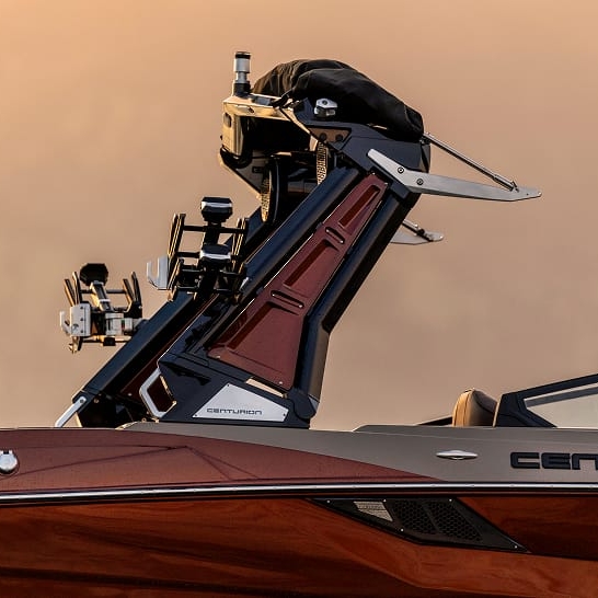 Close-up of the tower and equipment mounts on a Centurion Fe Series boat, highlighting detailed hardware, personalized features, and part of the windshield against a blurred background.