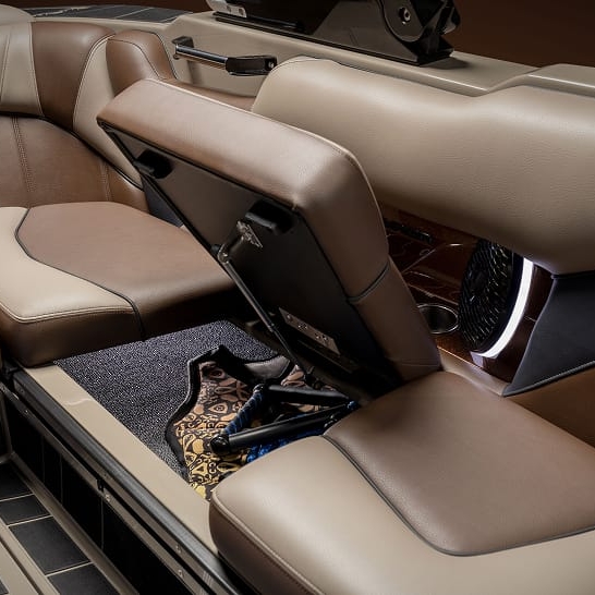 A storage compartment under a tan and brown Fe Series boat seat is open, revealing stored items on a carpeted area beneath—one of the features personal to this model.