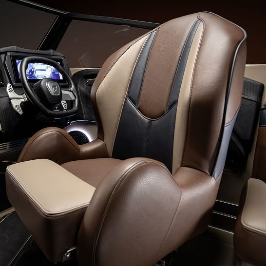 Close-up of a luxurious brown, beige, and black leather captain's chair inside a modern Fe Series boat cockpit, with personalized features on the control panel and digital displays visible in the background.