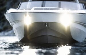 Photo of the front of a boat with two headlights on, floating on water.