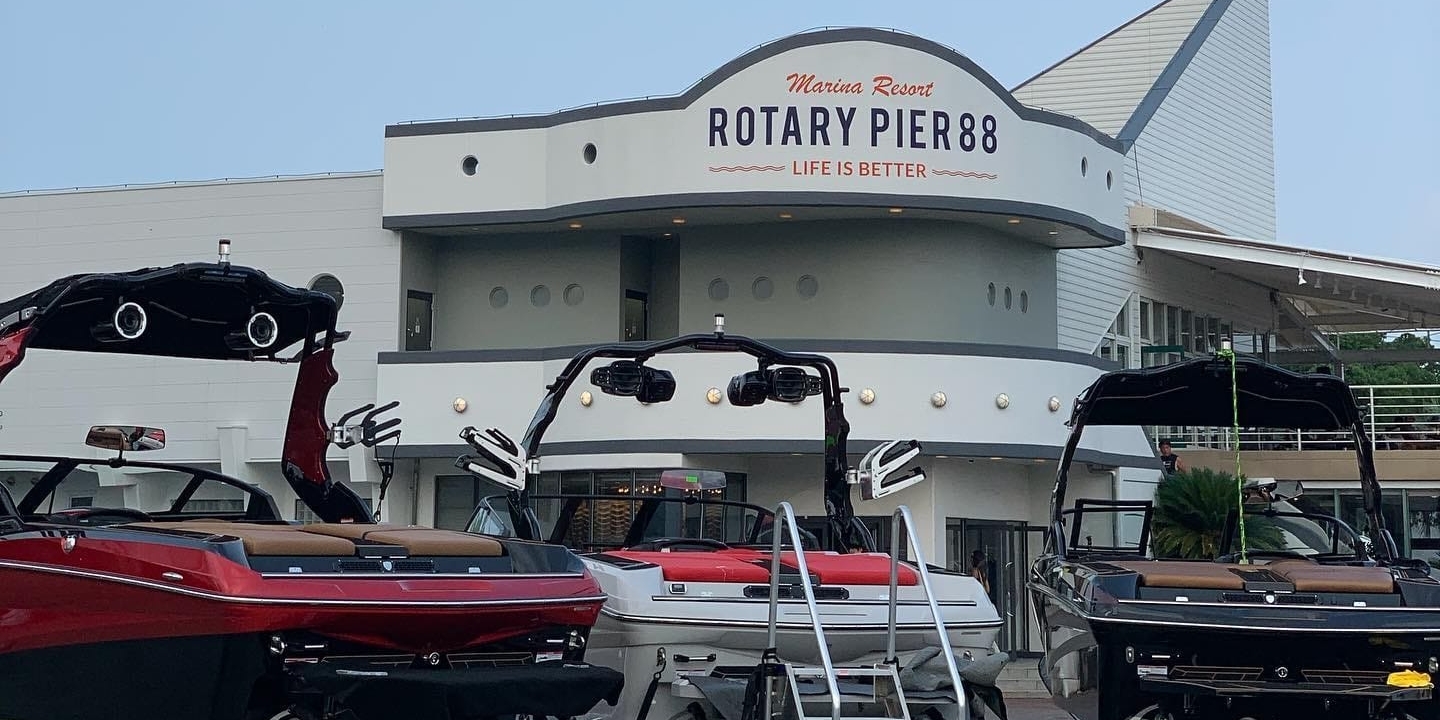 Front view of Rotary Pier 88 at Mansa Resort, showcasing several docked boats and the entrance to the pier building with signage 