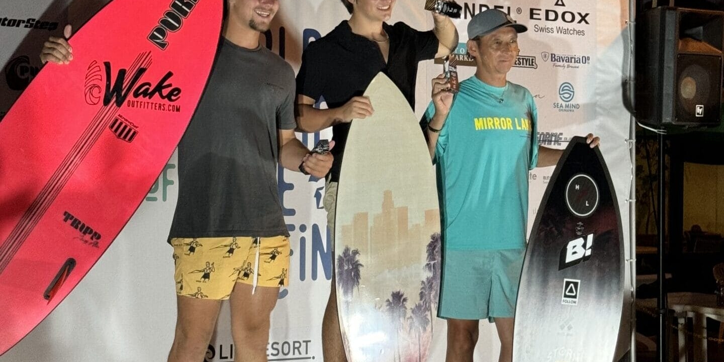 Three people stand on a winners' podium at the Centurion Wake Surf Japan Open 2024, each holding surfboards and trophies. The backdrop features event and sponsor logos.
