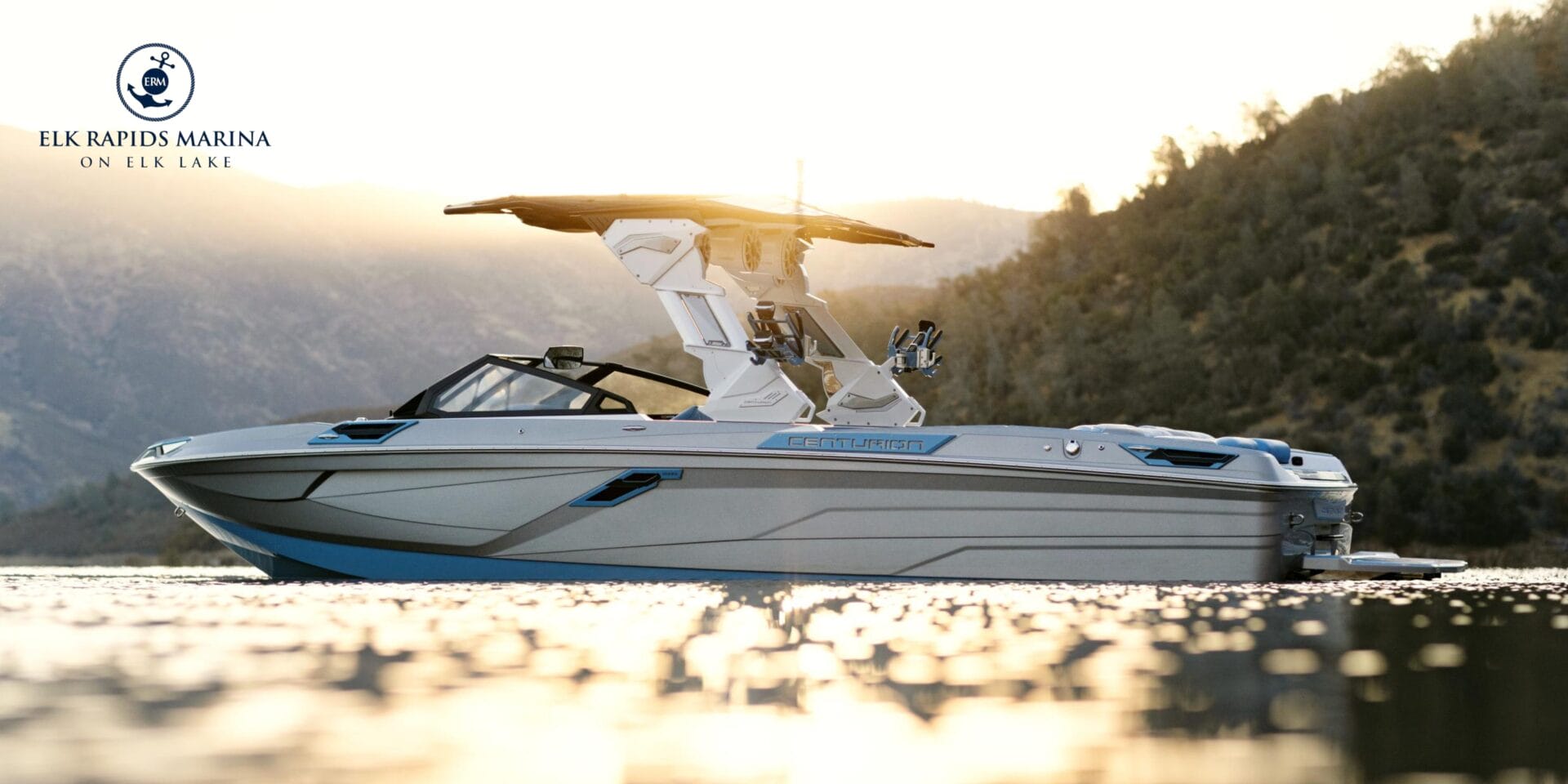A sleek motorboat is on a lake at sunset with hills in the background. The logo reads 