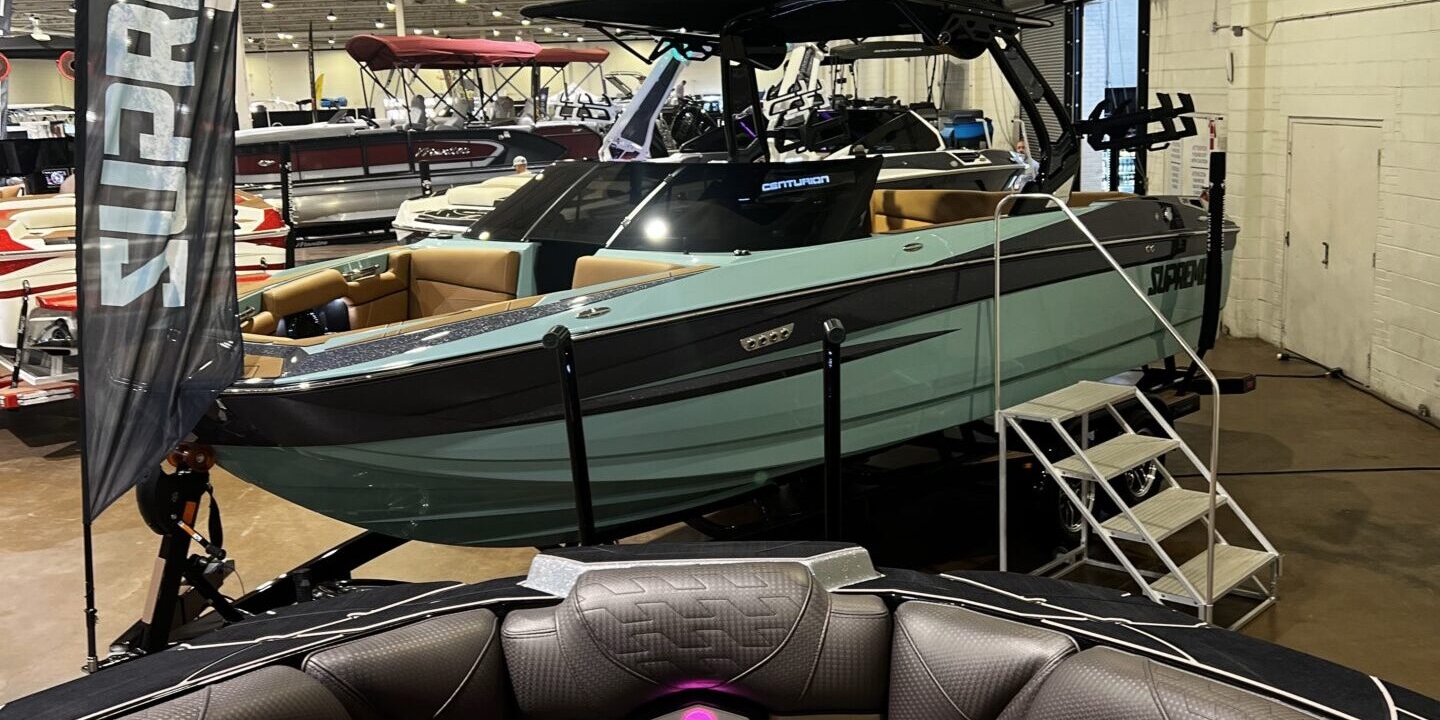 A boat showroom with various models, prominently featuring a green and black watercraft labeled 