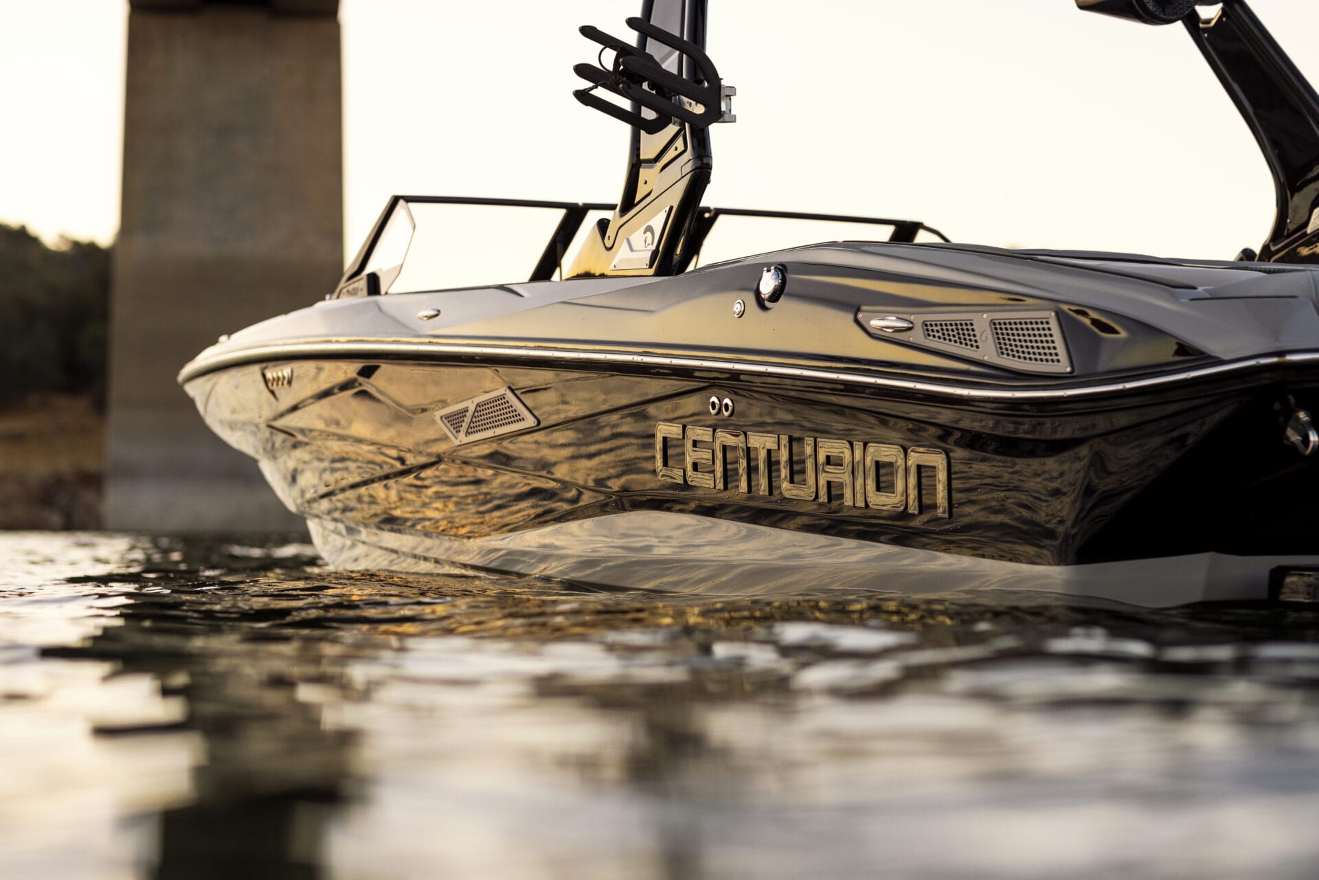 A sleek motorboat with the brand name "Centurion" is pictured on the water near a concrete bridge.