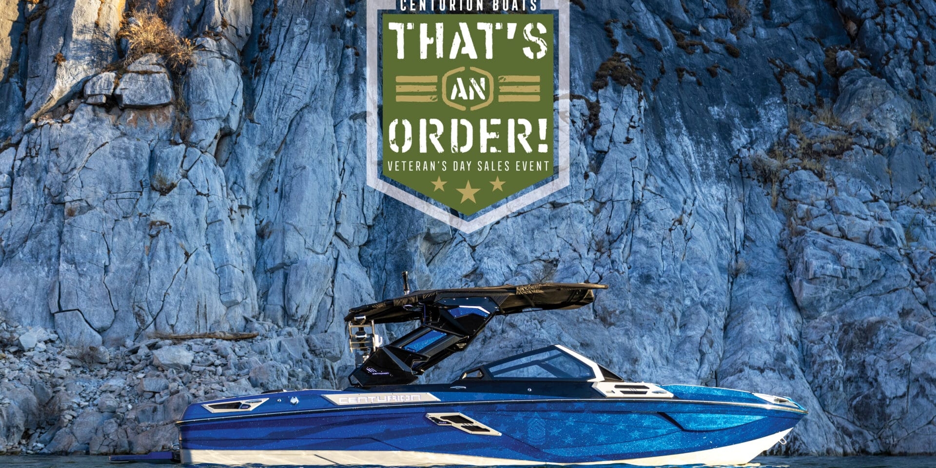 A blue and white boat floats on water near a rocky cliff. A large green and white sign above reads 