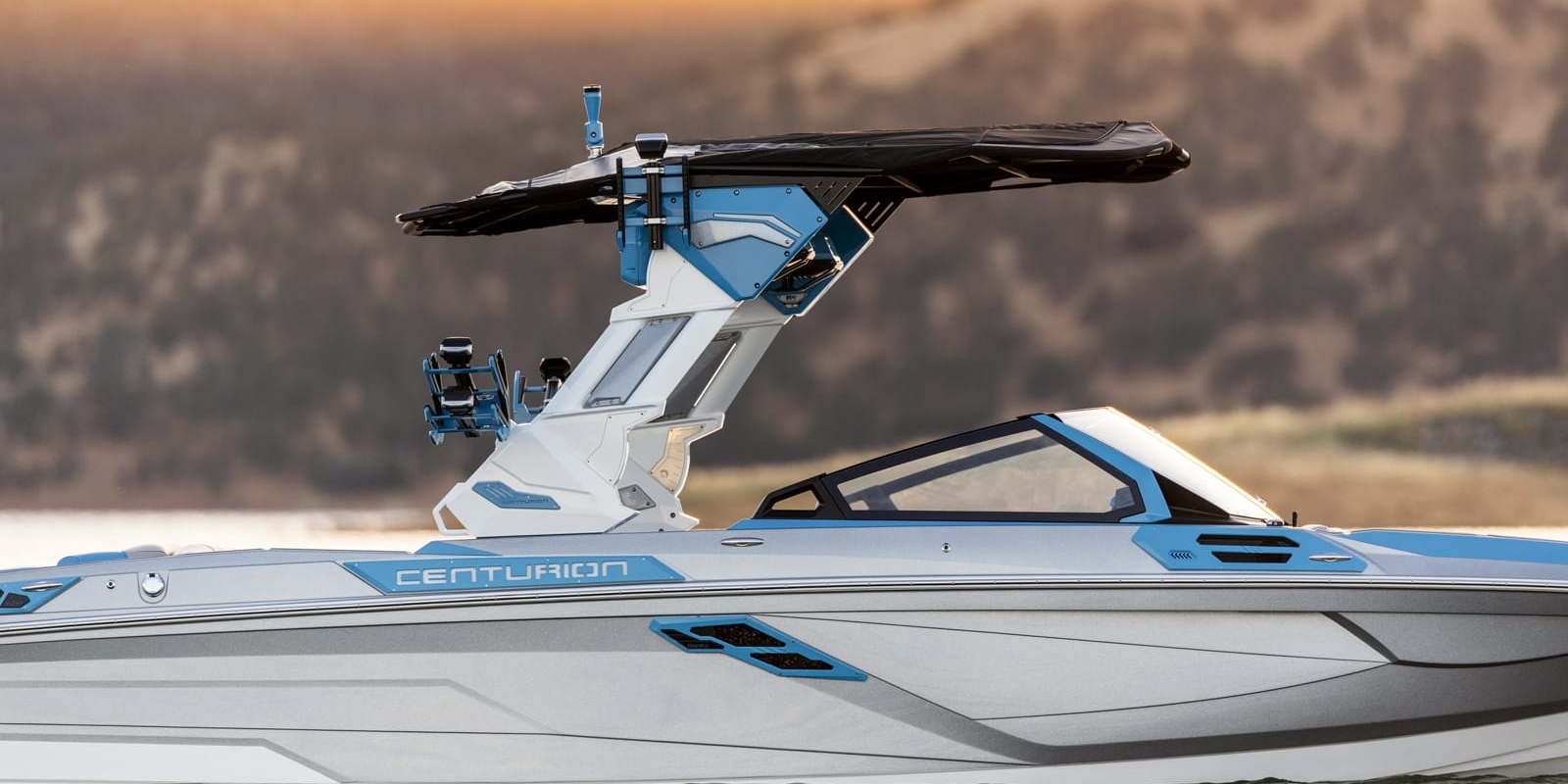 A sleek Centurion boat with a modern blue and white design, featuring a black canopy, cruising on calm water.