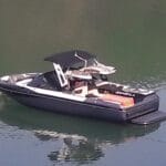 A motorboat with a black hull and canopy floating on calm water.