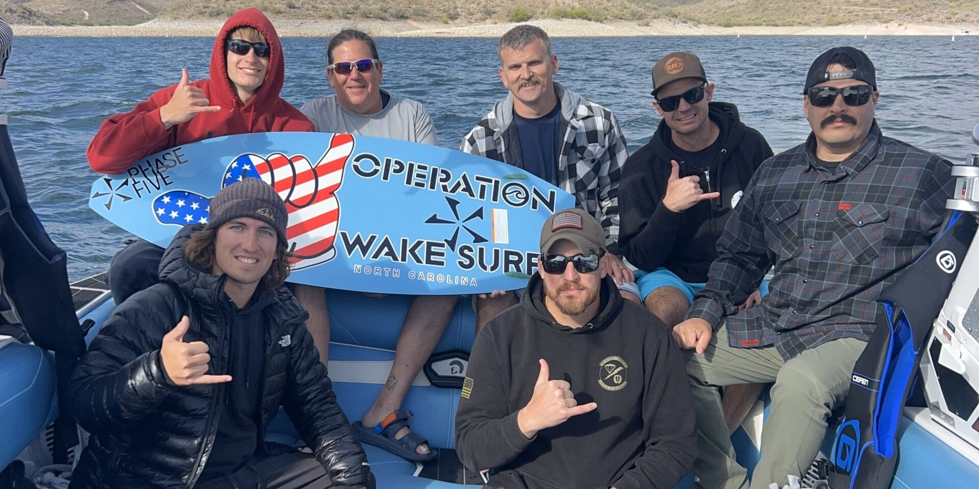 Group of seven men on a boat holding a