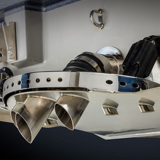 Close-up view of a boat’s dual stainless steel exhaust outlets and related marine hardware mounted on the transom.