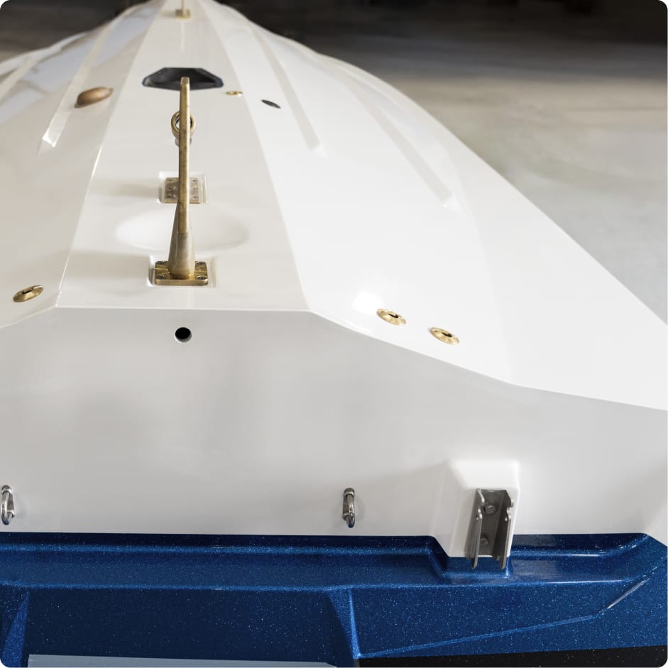 Close-up view of the bottom of a white boat hull with a blue keel, featuring metal fittings and hardware on a smooth surface—showcasing Centurion Boat fuel efficiency through its sleek, hydrodynamic design.