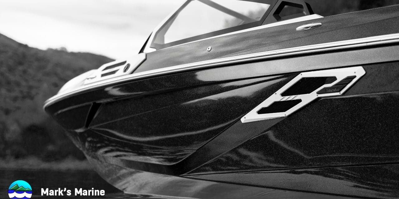 Close-up, side view of a sleek, modern speedboat on the water; hills in the background; Mark’s Marine logo and name in the lower left corner.