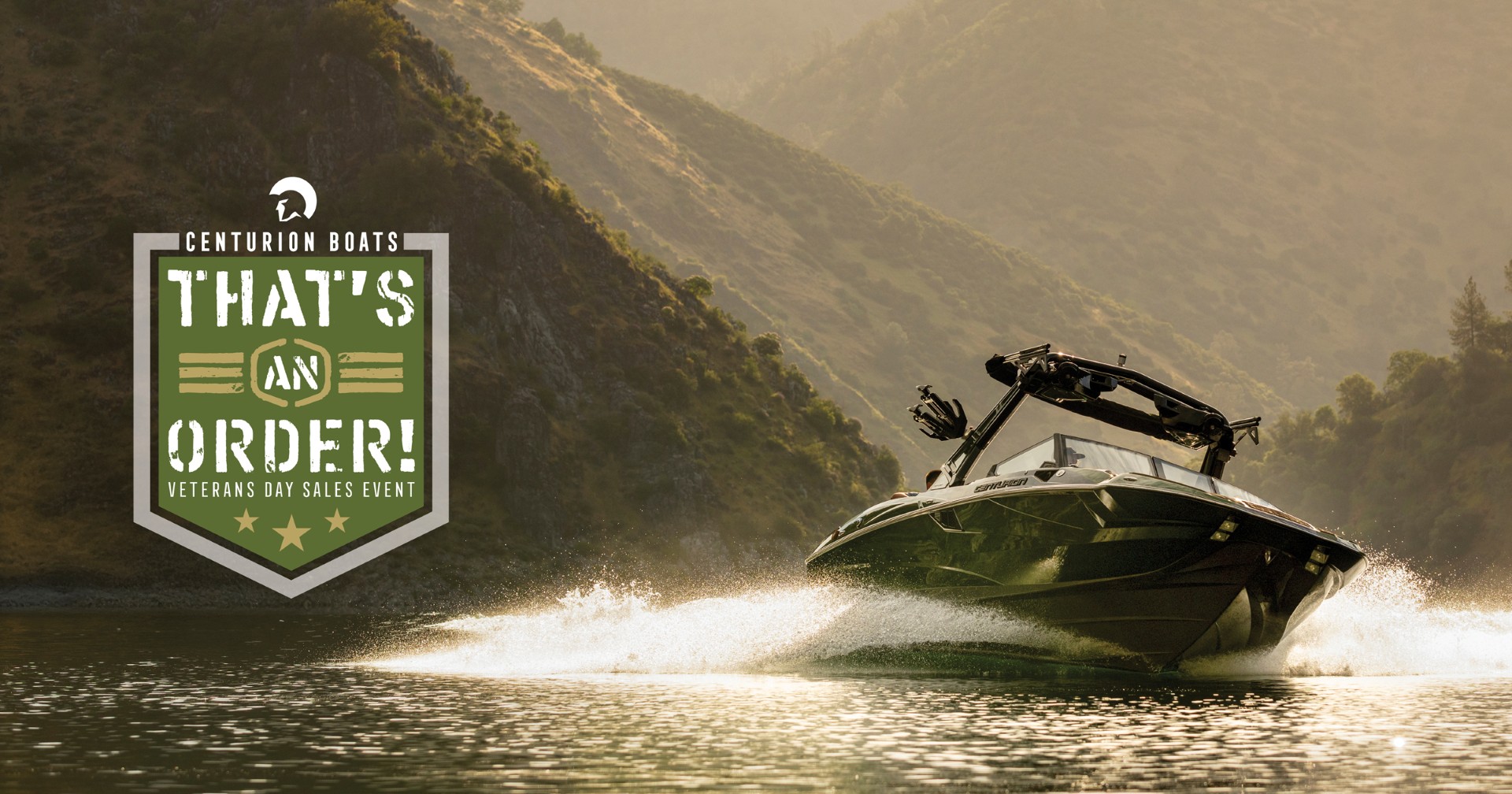 Speedboat moves quickly on a lake with mountains in the background; on the left, a Centurion Boats Veterans Day Sales Event badge reads “That’s an Order!”.