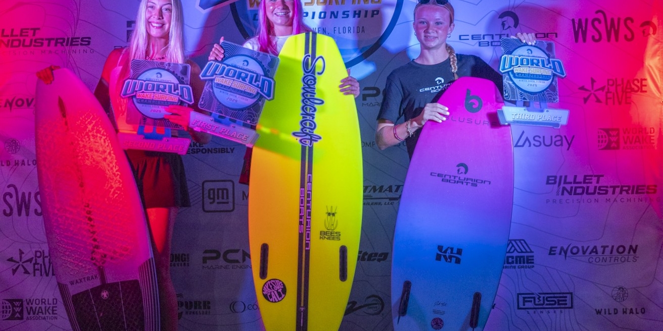 Three surfers stand on a podium holding surfboards and plaques for 1st, 2nd, and 3rd place at the Centurion World Surfing Championship, with a branded backdrop behind them.